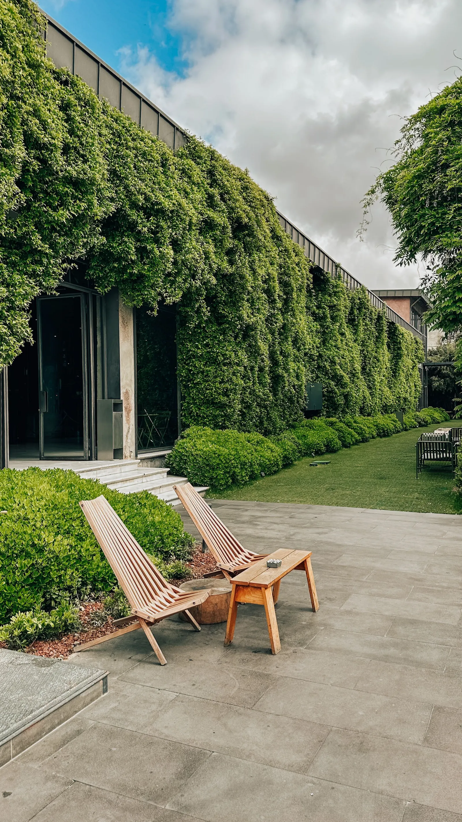 Terras met houten ligstoelen langs een begroeide muur